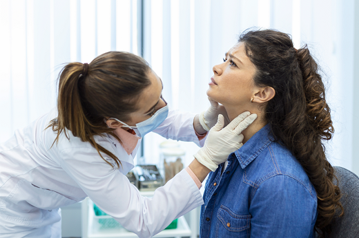 Imagem: Médica observando e tocando garganta de paciente mulher
