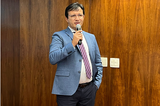 Imagem: Foto do reitor Custódio Almeida discursando com um microfone, vestindo um paletó azul 