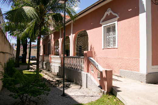 Imagem: Vista lateral da fachada do CEMUFC, casa rosa com três janelões gradeados (Foto: Ribamar Neto/UFC Informa)