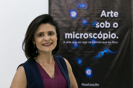 Imagem: A Profª Virgínia Girão, do Departamento de Morfologia da FAMED, explica que as exposição mostra imagens de microorganismos causadores de epidemias e apresenta o desenvolvimento das pesquisas ao microscópio e seus benefícios para a ciência (Foto: Viktor Braga/UFC)