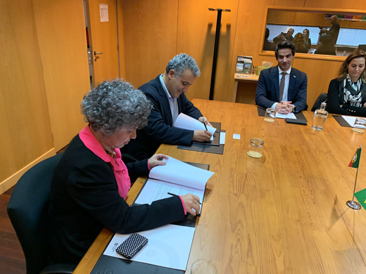 Imagem: Sentada em um Gabinete, vice-reitora (em primeiro plano) assina convênio com dirigentes do Instituto politécnico de Leiria, em Portugal. (Foto: Divulgação)