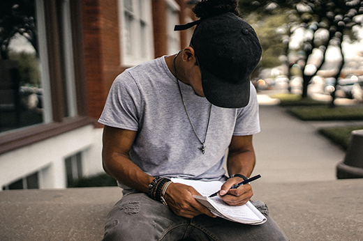 Imagem: jovem negro escreve em caderno