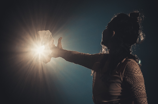 Imagem: foto de uma jovem na sombra tocando uma luz amarela