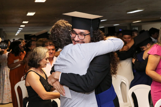 Imagem: formando Mateus Andrade abraça familiar durante cerimônia de colação