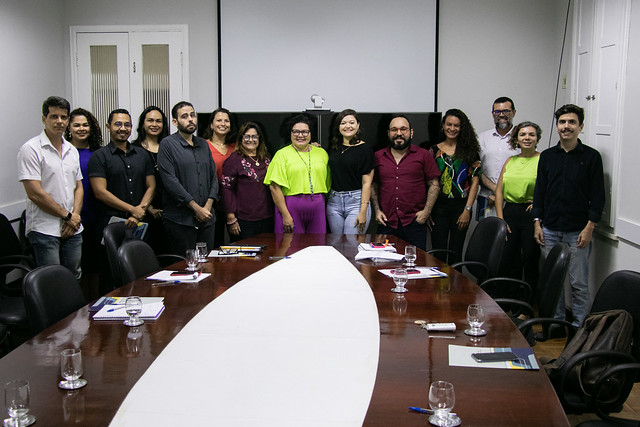 Imagem: pessoas em volta de uma mesa de reunião posam para foto