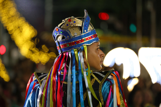 A ação da Procult tem como objetivo celebrar a tradição do Reisado na Universidade e na comunidade de Fortaleza (Foto: Viktor Braga/Secom-UFC) Imagem: Homem jovem vestido com traje de reisado em apresentação nos jardins da Reitoria da UFC