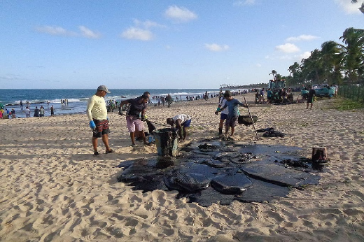 Foto de pessoas tirando óleo de uma praia