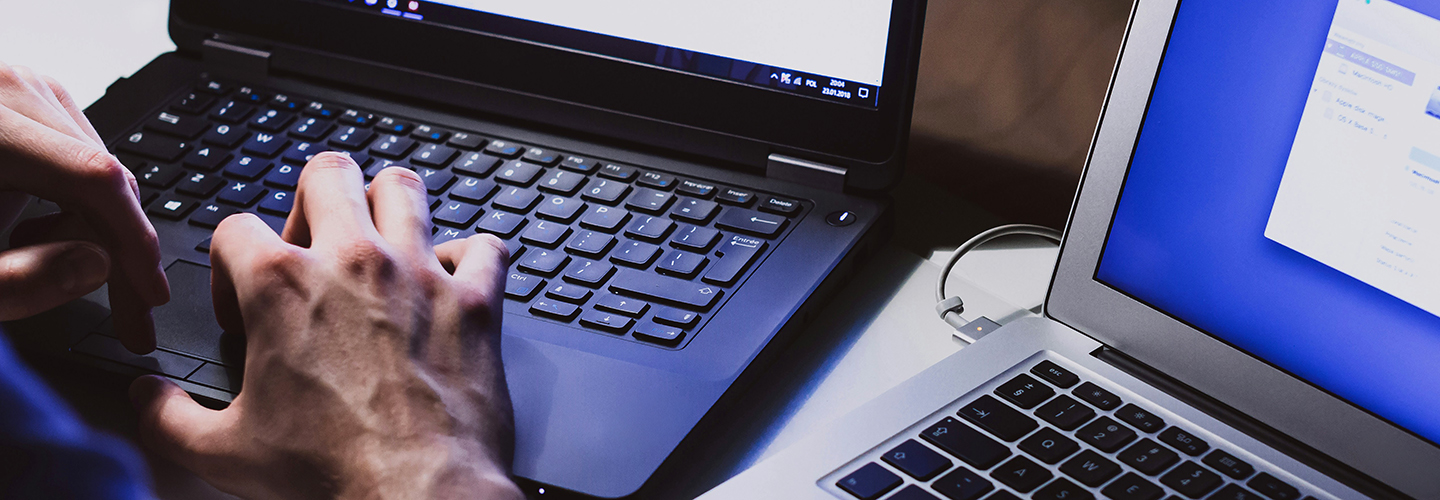 Mão digita em teclado de laptop preto