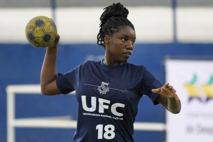 Mulher negra com camisa da UFC segurando bola de handebol